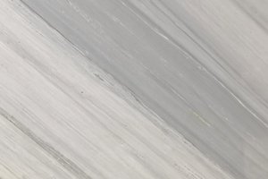 A white marble with soft linear veining and subtle tonal variation.