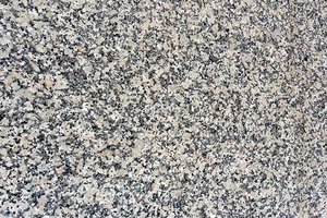 A coarse grained, cream granite with grey and taupe spots.
