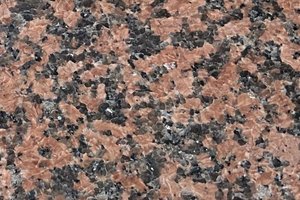 A red granite with dense black and charcoal speckling and a tight crystalline pattern.