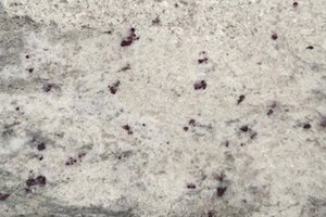 A white granite with soft gray movement and scattered burgundy flecks.