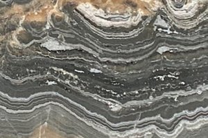 A gray and amber onyx with dramatic banded patterns and layered mineral swirls.