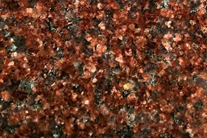 A red granite with fine, evenly distributed black and dark mineral speckling.