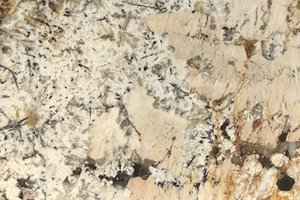 A cream granite with black mineral clusters and warm beige movement.