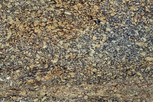 A coarse grained, gold and brown granite with black spots.
