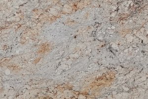 A cream and beige granite with broad movement and scattered gray and rust accents.