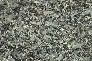 A green granite with olive and gray tones, dense speckling, and crystalline movement.