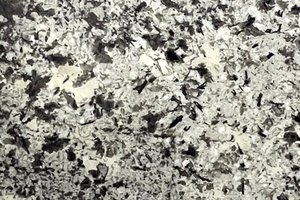 A white granite with black mineral clusters and scattered crystalline patterns.