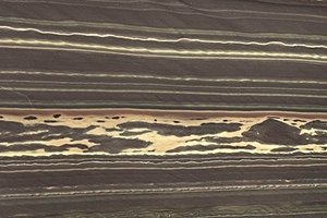 A dark brown granite with linear banding and thin cream and tan veins.