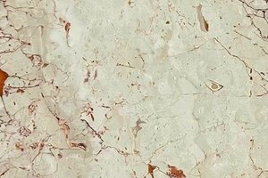 A cream marble with fine reddish veining and scattered rust-toned accents.