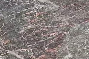 A gray marble with soft white movement and subtle pink undertones.