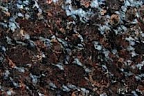 A granite with a black background with random red and brown flakes.